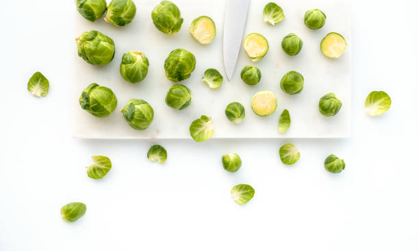 Brussels Sprouts and Knife on White Marble Brussels sprouts and knife on marble chopping board and white background. chopping food photos stock pictures, royalty-free photos & images