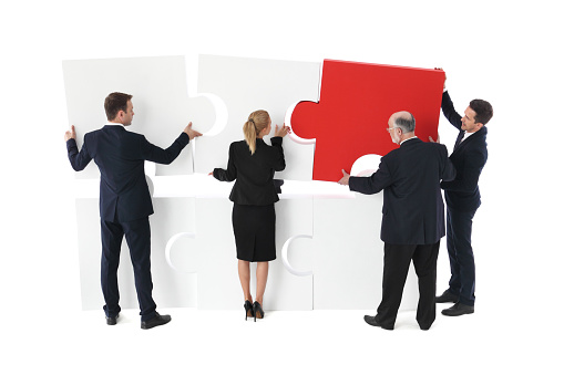 Business team builds a new project with puzzle, isolated on white