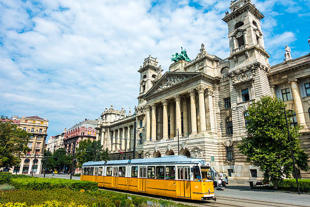 Budapest, Hungary - August 19, 2016: yellow tram with passengers in Budapest in front of Museum of Ethnography