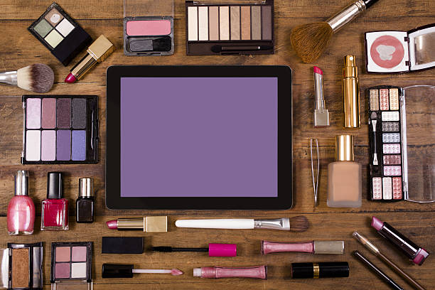 varios cosméticos rodean una tableta digital en el tocador. - red lipstick fotografías e imágenes de stock