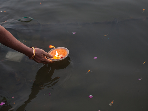 Puja with candle in human hand left on water for offering in Ganges River, Varanasi.Shot in daylight with a full frame DSLR camera.Horizontal composition.