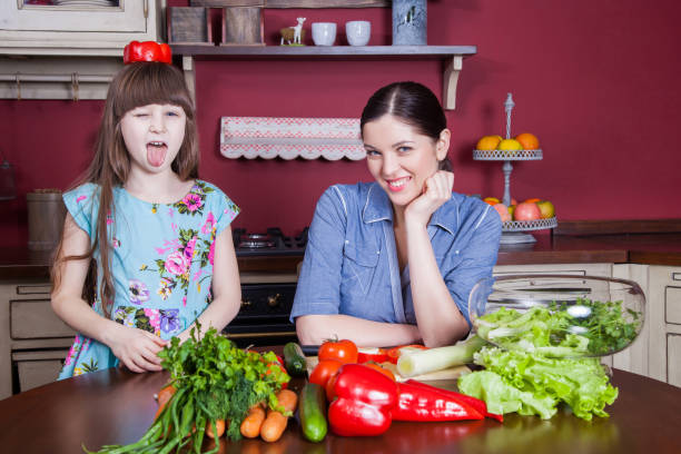 istock Mother and daughter having fun and making vegetable salad together. 638597210