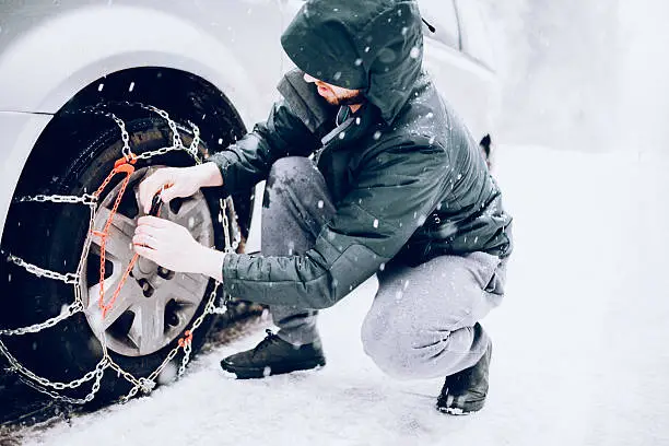Photo of Man Putting Snow Tire Chains On Car