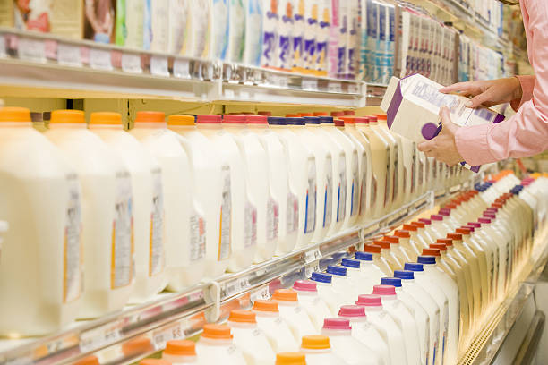 Woman checking ingredients on back of milk carton in supermarket Woman checking ingredients on back of milk carton in supermarket milk jug stock pictures, royalty-free photos & images