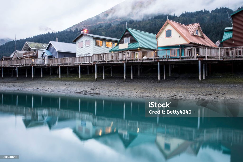 Colorful houses beneath fog and above water in Seward, Alaska. Water reflections of colorful houses early in the morning. Alaska - US State Stock Photo