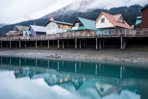 Colorful houses beneath fog and above water in Seward, Alaska. Water reflections of colorful houses early in the morning. seward alaska stock pictures, royalty-free photos & images