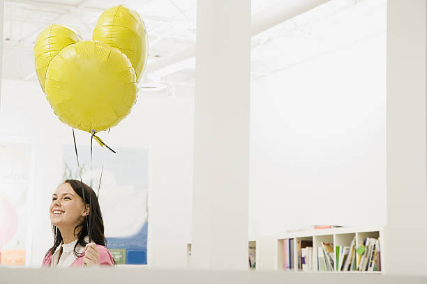 Woman holding helium balloons in office