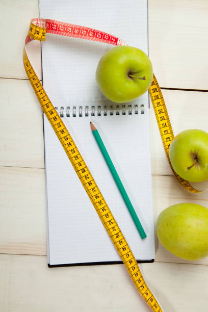 istock Green apples with measuring tape on a white wooden table 638610488