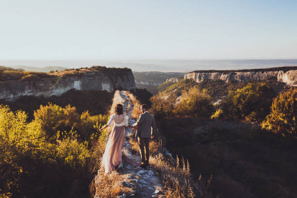 istock Bride and groom walking in mountains at sunset 638619762