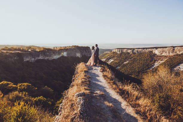 istock Bride and groom walking in mountains at sunset 638620486