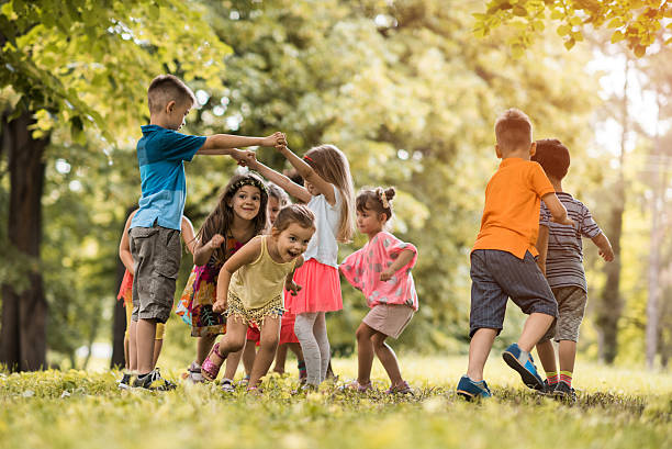 groupe de petits enfants s'amusant tout en jouant dans la nature. - play photos et images de collection