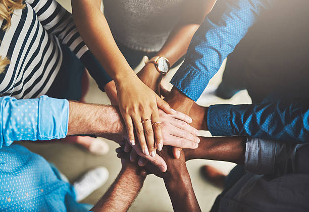 Getting it done through teamwork Shot of a group of creative businesspeople standing with their hands in a huddle huddle stock pictures, royalty-free photos & images