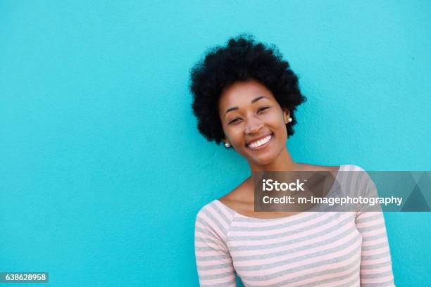 Cheerful Woman Standing Against Blue Wall Stock Photo - Download Image Now - Colored Background, Women, Headshot