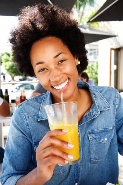 istock Smiling woman drinking orange juice at cafe 638631196