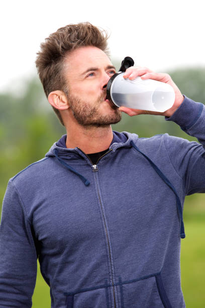 istock Fit older runner standing in park drinking water 638634666