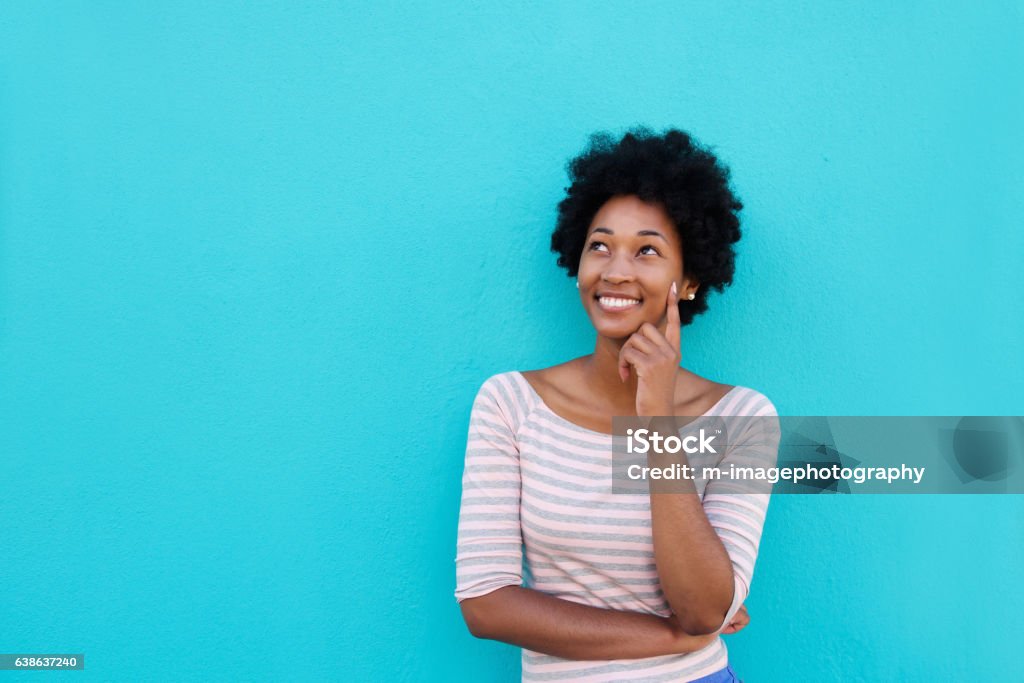 Bella giovane donna africana sorridente e pensa - Foto stock royalty-free di Donne