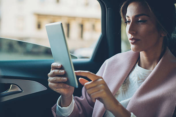 femme avec tablette numérique dans une voiture - high society luxury women upper class photos et images de collection