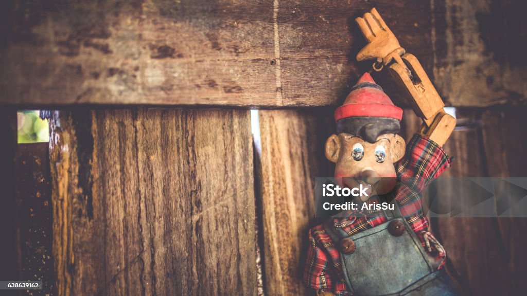 Vintage Photo Vintage pinocchio puppet doll on the old grunge wooden wall in horizontal picture. Adult Stock Photo