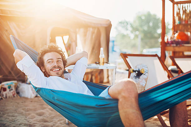 Lazy summer afternoon Smiling young man resting in a hammock in a summer camp. hammock stock pictures, royalty-free photos & images