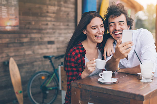 Sharing the positive emotions Young woman and man drinking coffee and looking at a smart phone outdoors in the summer, with copy space. espresso photos stock pictures, royalty-free photos & images