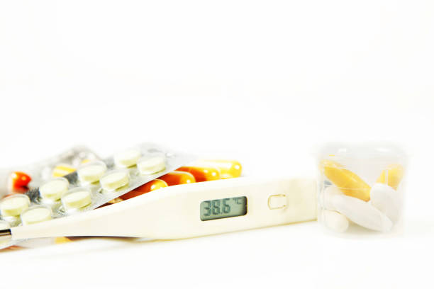 istock Fever. Thermometer with elevated temperature and various pills 638639630