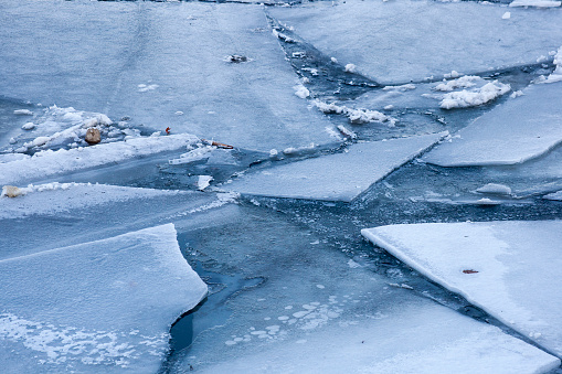 Big ice fragments covered with snow on frozen river