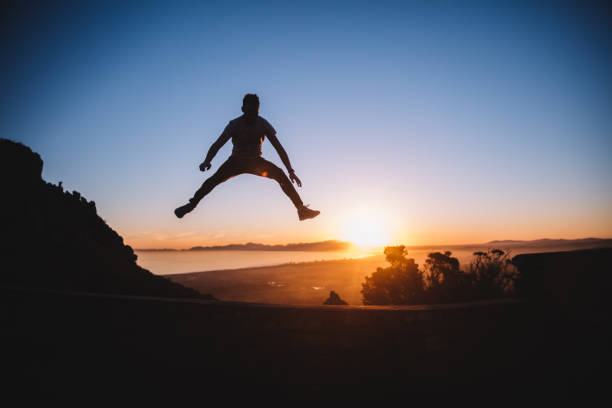 istock Silhouette of cheerful young man jumping in sunset 638640568