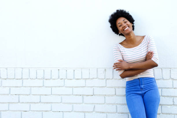 istock Smiling woman standing with arms crossed by white wall 638642850