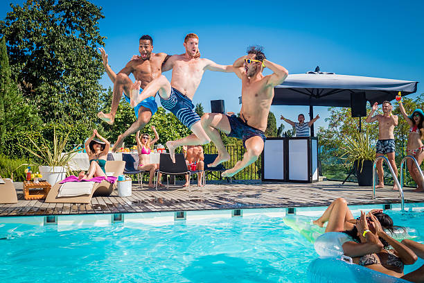 Friends diving into pool Friends jumping into the pool doing funny poses male swimsuit standing arm around stock pictures, royalty-free photos & images