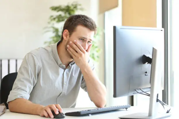 Worried businessman working trying to solve troubles on line with a desktop computer at office