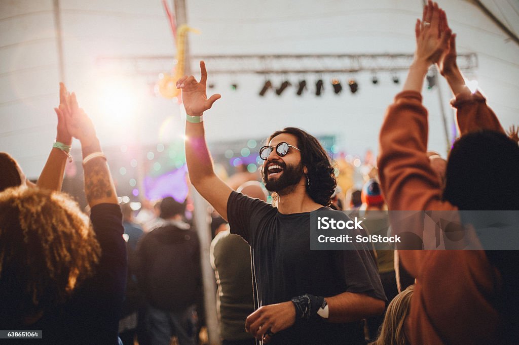 Festival Vibes People are dancing in a performance tent at a music festival. The main focus is on a man who is wearing sunglasses and is dancing with a hand in the air. Music Festival Stock Photo