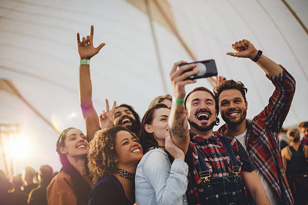 Festival Selfie Group of young adult friends are taking a group selfie on a smartphone while they are at a festival. tent photos stock pictures, royalty-free photos & images