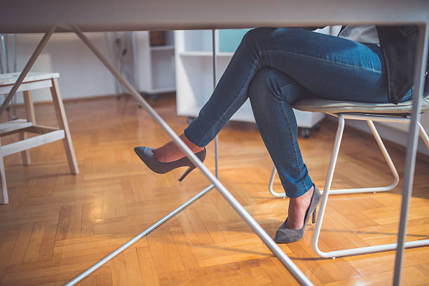 Legs and high heels Low angle view on legs while sitting at the office table woman sitting cross legged in chair stock pictures, royalty-free photos & images