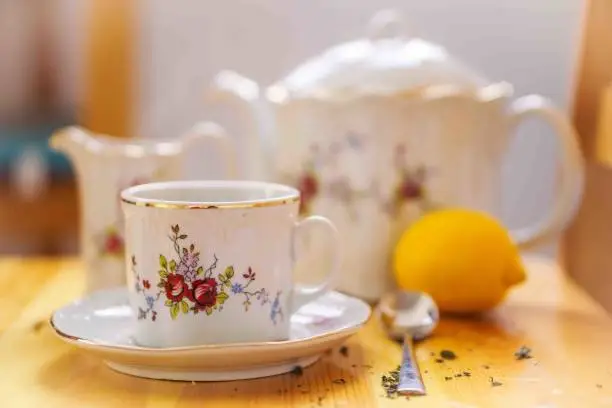drinks, relaxation and tea concept - tea cup, pot, spoon, lemon and saucer