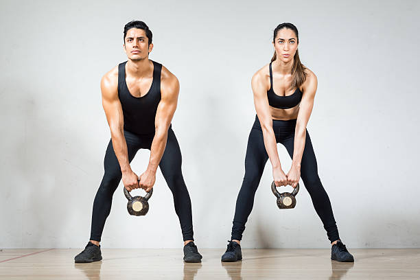 bella coppia ispanica che solleva kettlebells insieme - kettle bell sport women muscular build foto e immagini stock