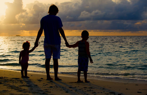 istock father with kids silhouettes walk at sunset beach 638661518
