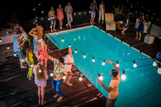 Friends enjoying pool party Happy friends dancing and enjoying pool party at poolside. feeding grapes stock pictures, royalty-free photos & images