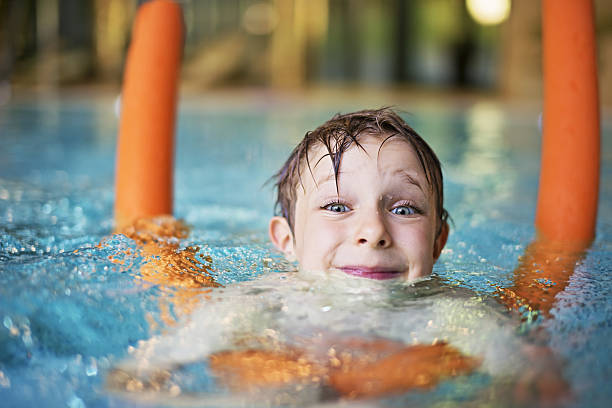 mały chłopiec nauki pływania w basenie z makaronem - swimming child swimming pool indoors zdjęcia i obrazy z banku zdjęć