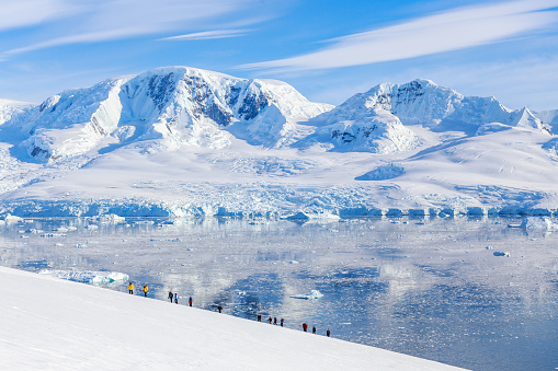 Group of people hiking the snowy mountains, Neco bay, Antarctic