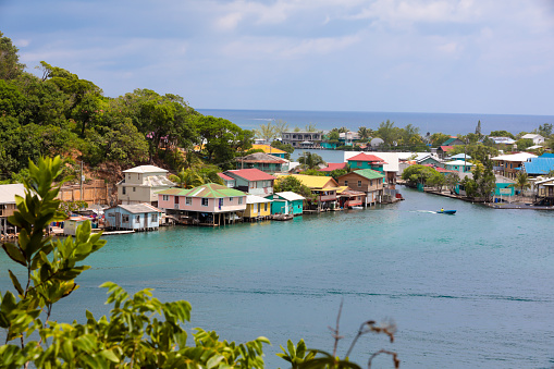 *3 logo rule. Scenic view of a seaside village on  Roatain, which is part of the Bay Islands of Hondouras. It is the largest of the Bay Islands and an eco-tourism destination. Colorful wooden stilt homes dot the landscape. Taken with Canon 5D Mark lV.