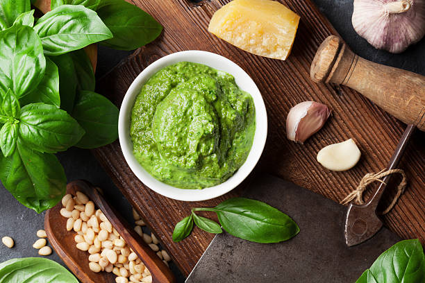 Pesto sauce ingredients Pesto sauce cooking. Basil, olive oil, parmesan, garlic, pine nuts. Top view on dark stone table pesto sauce stock pictures, royalty-free photos & images