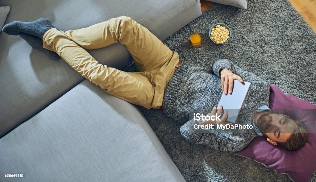 Man laying on floor using digital tablet Men, People, Reading, Looking,  Tablet, Young Adult, E-Reader Stock Photo