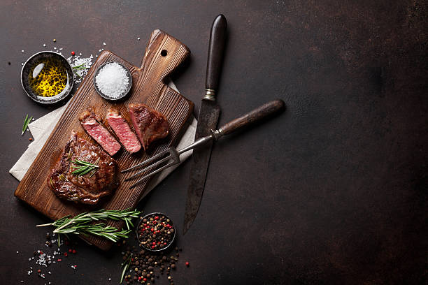 Grilled ribeye beef steak, herbs and spices Grilled ribeye beef steak, herbs and spices. Top view with copy space for your text kitchen utensil photos stock pictures, royalty-free photos & images