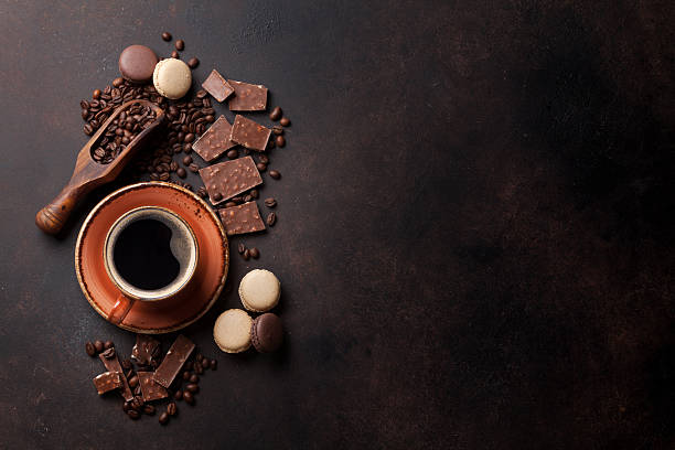 Coffee cup, chocolate and macaroons on old kitchen table Coffee cup, beans, chocolate and macaroons on old kitchen table. Top view with copyspace for your text texture cafe stock pictures, royalty-free photos & images