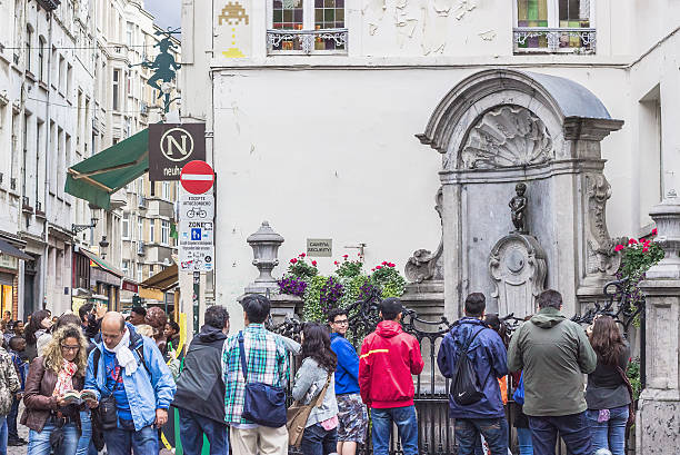 Manneken Pis, statue of a pissing boy in Brussels, Belgium Brussels, Belgium - August 22, 2014: People looking at Manneken Pis statue in Brussels. Statue of a pissing boy, an iconic symbol of the Belgian Capital manneken pis statue in brussels belgium stock pictures, royalty-free photos & images