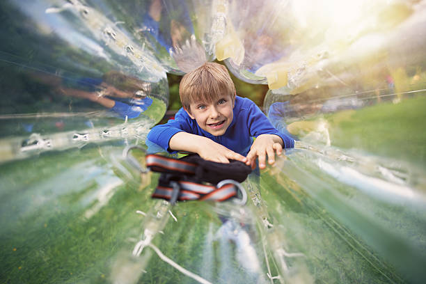 Little boy entering inside a zorb sphere Little boy inside a zorb sphere in amusement park. zorbing stock pictures, royalty-free photos & images