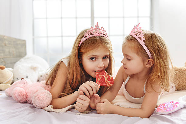 istock Charming sisters enjoying candy at home 638678128