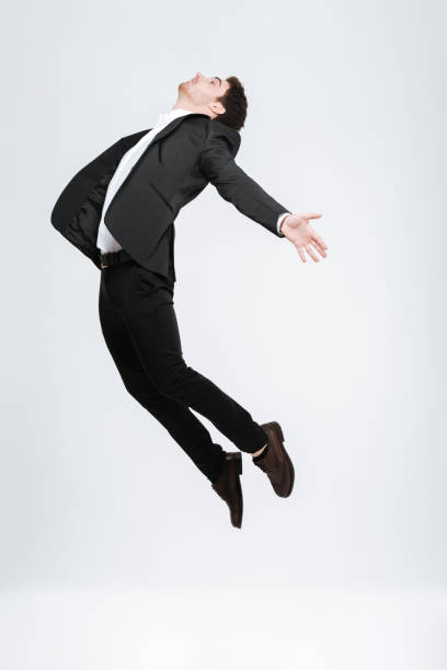 istock Young happy business man in black suit flying in studio 638678462