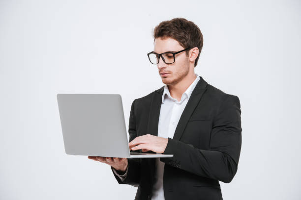 istock Handsome young businessman in eyeglasses standing and using laptop 638680732