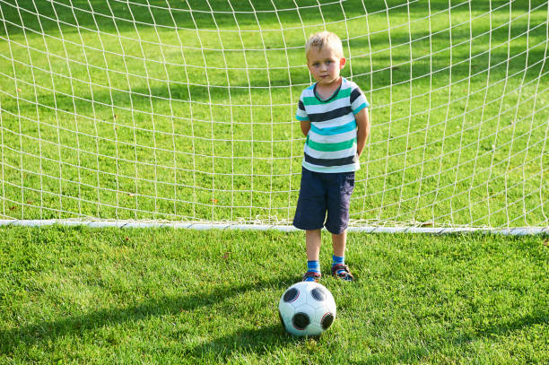 netter kleiner blonder junge, der als torwart spielt - playing field goalie soccer player little boys stock-fotos und bilder